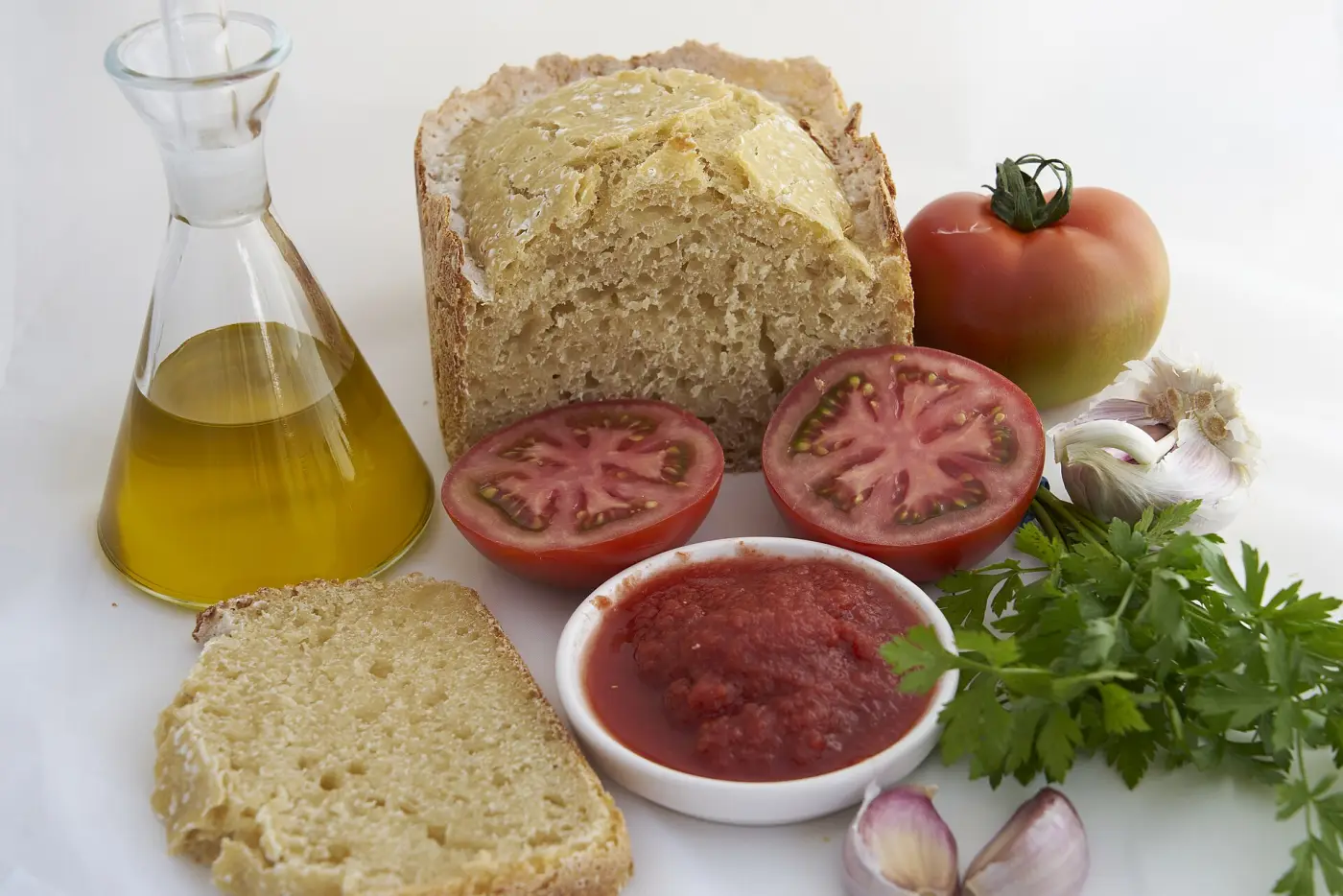 Pan, tomate, ajo y una aceitera con aceite de oliva virgen extra en una mesa de desayuno
